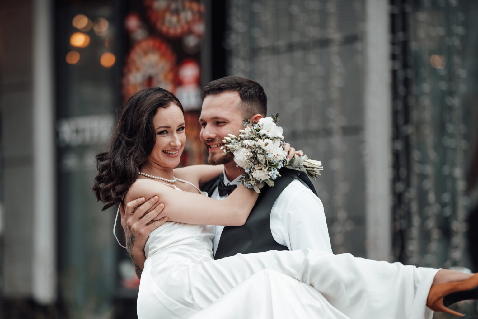 Braut wird vom Bräutigam in der Stadt auf Händen getragen